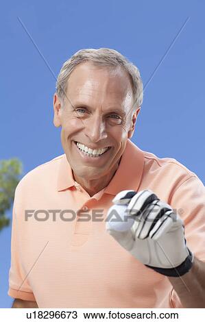Stock Image - Portrait of senior man holding golf ball. Fotosearch
