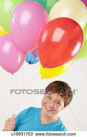 Portrait of smiling boy (12-13) holding balloons, studio shot View Large Photo Image Stock Image - Portrait of smiling boy (12-13) holding balloons, studio shot. Fotosearch