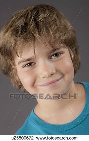 Stock Image - Portrait of smiling boy (8-9), studio shot. Fotosearch