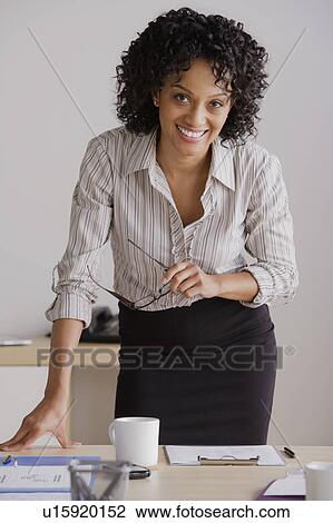 Stock Image - Portrait of smiling businesswoman in office. Fotosearch