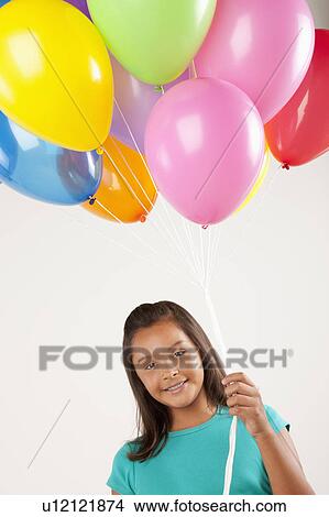 Portrait of smiling girl (10-11) holding balloons, studio shot View Large Photo Image Picture - Portrait of smiling girl (10-11) holding balloons, studio shot. Fotosearch