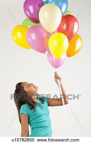 Portrait of smiling girl (10-11) holding balloons, studio shot View Large Photo Image Stock Image - Portrait of smiling girl (10-11) holding balloons, studio shot. Fotosearch