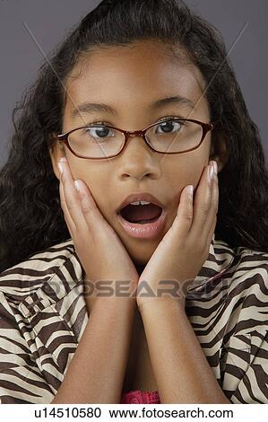 Stock Image - Portrait of surprised girl (8-9), studio shot. Fotosearch