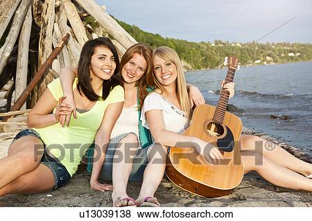 Stock Photo - Portrait of three young women hanging out on beach. Fotosearch