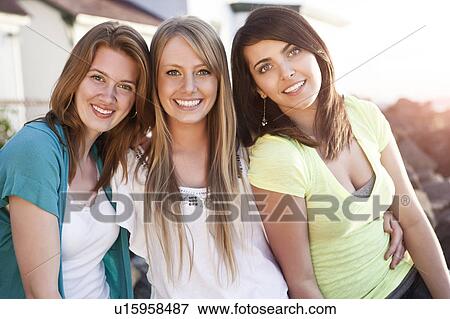 Stock Photo - Portrait of three young women smiling. Fotosearch