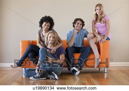 Picture - Portrait of two couples sitting on sofa. Fotosearch