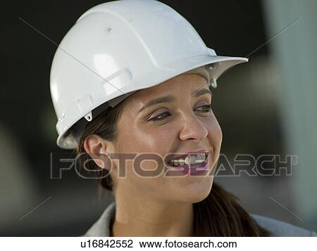 Stock Image - Portrait of woman wearing hardhat. Fotosearch