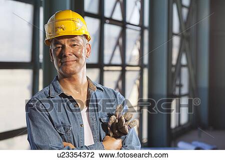 Stock Image - Portrait of worker wearing hardhat. Fotosearch