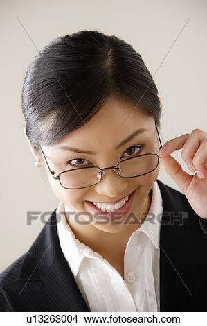 Picture - Portrait of young businesswoman looking over glasses. Fotosearch