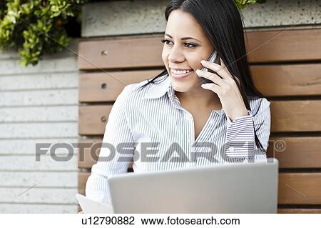 Portrait of young businesswoman sitting on bench using laptop View Large Photo Image Stock Image - Portrait of young businesswoman sitting on bench using laptop. Fotosearch
