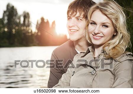 Portrait of young couple embracing by lake at sunset View Large Photo Image Stock Photo - Portrait of young couple embracing by lake at sunset. Fotosearch