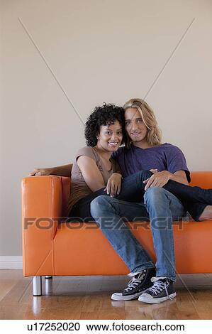 Portrait of young couple sitting on sofa View Large Photo Image Stock Image - Portrait of young couple sitting on sofa. Fotosearch