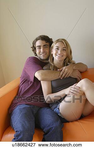 Portrait of young couple sitting on sofa View Large Photo Image Stock Photo - Portrait of young couple sitting on sofa. Fotosearch