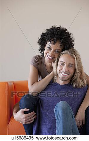Portrait of young couple sitting on sofa View Large Photo Image Stock Photography - Portrait of young couple sitting on sofa. Fotosearch