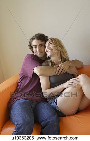 Stock Photography - Portrait of young couple sitting on sofa. Fotosearch