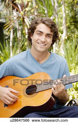 Stock Photograph - Portrait of young man playing guitar. Fotosearch