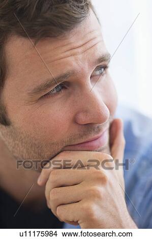 Picture - Portrait of young man with hand on chin. Fotosearch