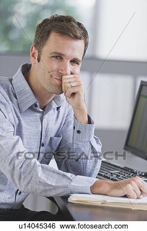 Portrait of young man working in office View Large Photo Image Stock Photograph - Portrait of young man working in office. Fotosearch