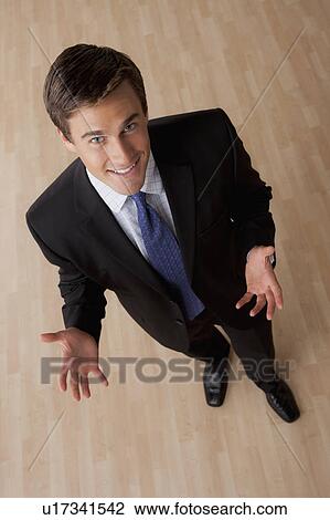 Stock Image - Portrait of young smiling businessman gesturing. Fotosearch