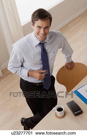Stock Image - Portrait of young smiling businessman in office. Fotosearch