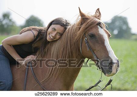 Stock Photo - Portrait of young woman riding horse. Fotosearch