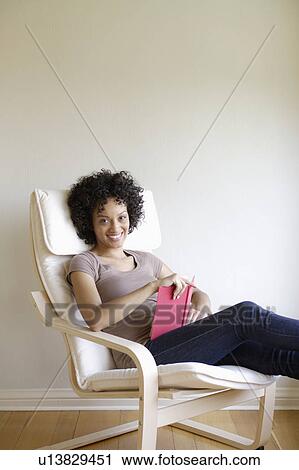 Portrait of young woman sitting in armchair View Large Photo Image Stock Image - Portrait of young woman sitting in armchair. Fotosearch
