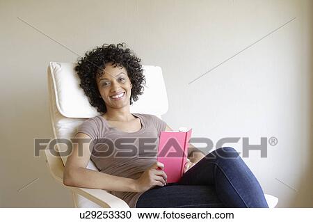 Portrait of young woman sitting in armchair View Large Photo Image Stock Image - Portrait of young woman sitting in armchair. Fotosearch