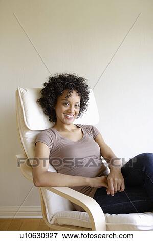 Stock Photo - Portrait of young woman sitting in armchair. Fotosearch