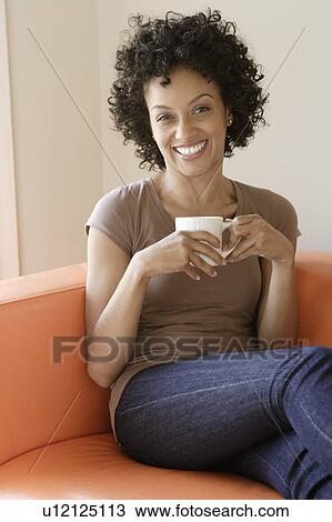 Portrait of young woman sitting on sofa View Large Photo Image Stock Image - Portrait of young woman sitting on sofa. Fotosearch