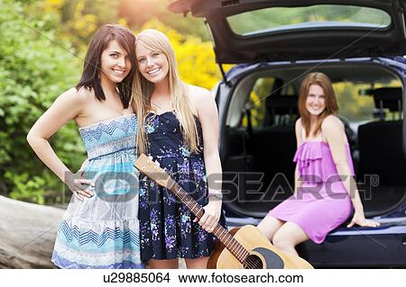 Portrait of young women with guitar by car View Large Photo Image Picture - Portrait of young women with guitar by car. Fotosearch