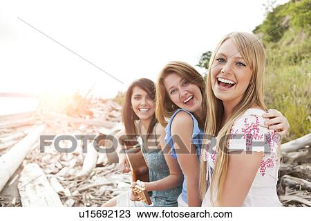 Stock Image - Portrait of young women with guitar on beach. Fotosearch