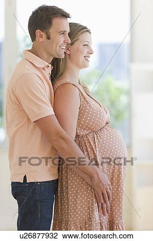 Pregnant woman and her partner standing together View Large Photo Image Stock Image - Pregnant woman and her partner standing together. Fotosearch