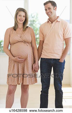 Stock Photo - Pregnant woman holding partner's hand. Fotosearch