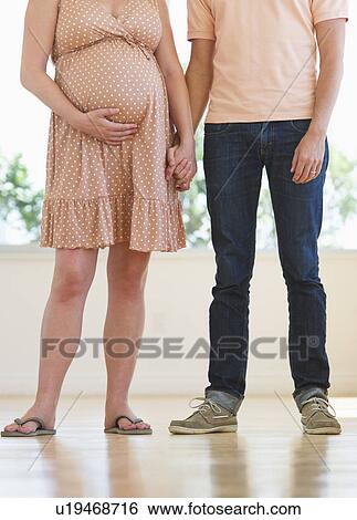 Stock Photograph - Pregnant woman holding partner's hand. Fotosearch