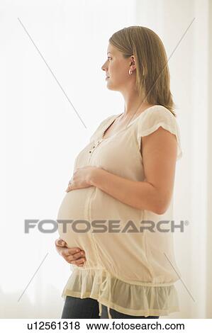 Pregnant woman looking through window View Large Photo Image Stock Photo - Pregnant woman looking through window. Fotosearch