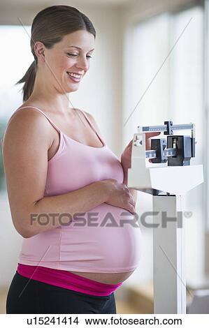 Pregnant woman weighing herself View Large Photo Image Picture - Pregnant woman weighing herself. Fotosearch