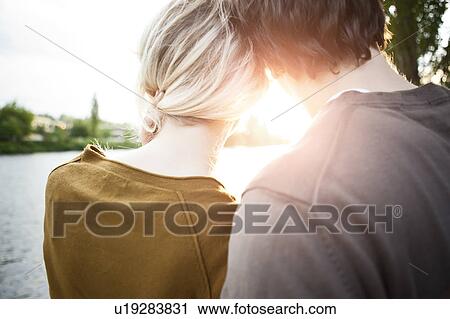 Stock Image - Rear view of young couple looking at sunset. Fotosearch