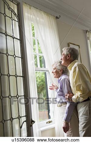 Stock Photo - Senior couple looking through window. Fotosearch