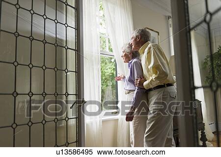 Stock Photography - Senior couple looking through window. Fotosearch