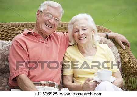 Stock Photography - Senior couple relaxing on outdoor sofa. Fotosearch