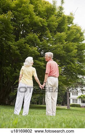 Stock Image - Senior couple standing in park. Fotosearch