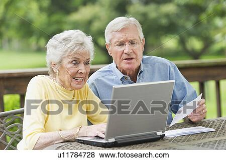 Stock Photo - Senior couple using laptop on porch. Fotosearch