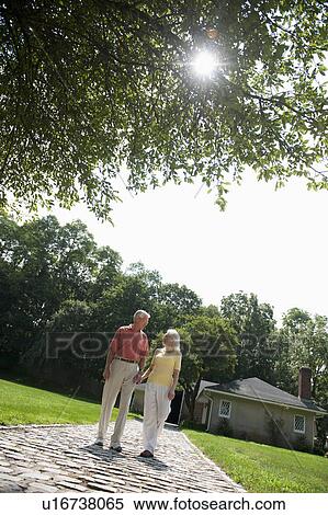 Stock Photography - Senior couple walking down footpath. Fotosearch
