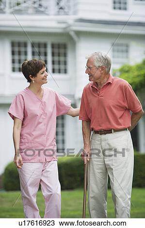 Senior man and nursing assistant walking in back yard View Large Photo Image Stock Image - Senior man and nursing assistant walking in back yard. Fotosearch