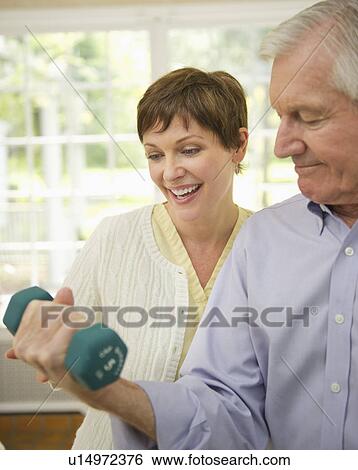 Senior man lifting dumbbell, nurse assisting him View Large Photo Image Stock Photograph - Senior man lifting dumbbell, nurse assisting him. Fotosearch