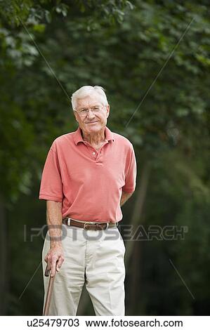 Senior man standing in park View Large Photo Image Stock Image - Senior man standing in park. Fotosearch