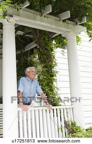 Stock Image - Senior man standing on porch. Fotosearch