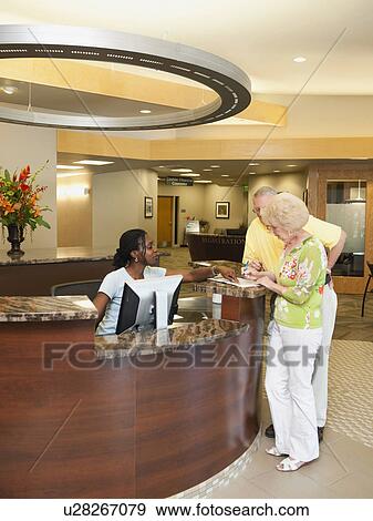 Stock Photo - Senior people at reception desk in hospital. Fotosearch