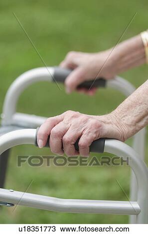 Stock Image - Senior walking with walker, close-up of hands. Fotosearch