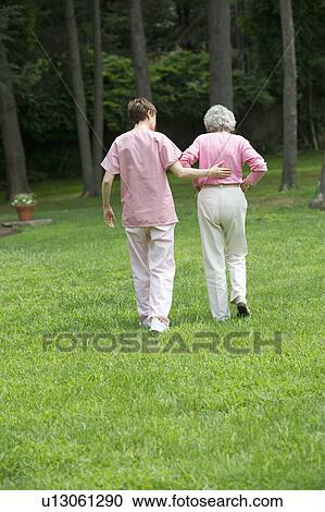 Senior woman and nursing assistant walking in back yard View Large Photo Image Stock Image - Senior woman and nursing assistant walking in back yard. Fotosearch